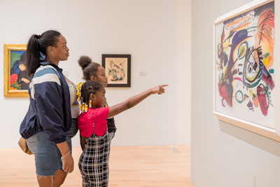 A family of four stands at the edge of Windover Hall and look up at the architecture in admiration.
